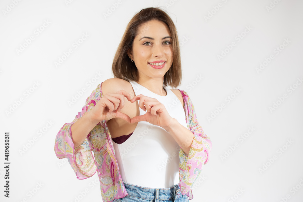 Young beautiful woman showing with her finger heart figure, sending love to her lover, standing over white background Young beautiful woman showing with her finger heart figure, sending love to her lover, standing over white background