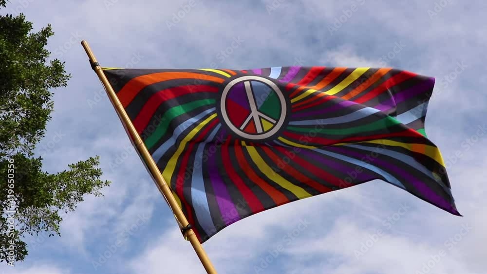 Colourful flag with a white peace sign on it slowly blowing in the wind. Colourful flag with a white peace sign on it slowly blowing in the wind.