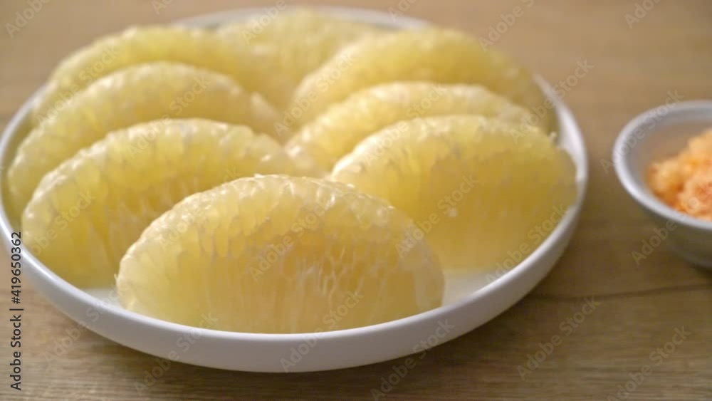 Fresh peeled pomelo, grapefruit or shaddock on white plate Fresh peeled pomelo, grapefruit or shaddock on white plate