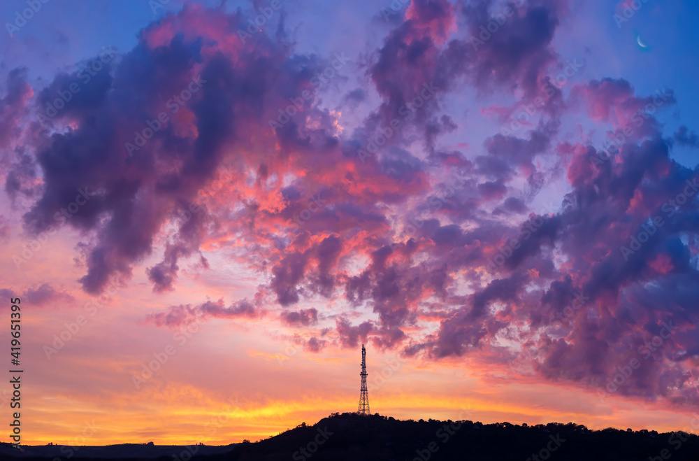 silhouette of radio telecommunication tower on colorful cloudy morning sky