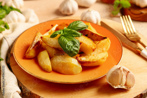 Plate of tasty baked potatoes with garlic on table