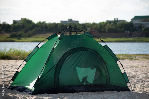Tourist tent on sandy bank against river background. Camping rest outside the city © somemeans