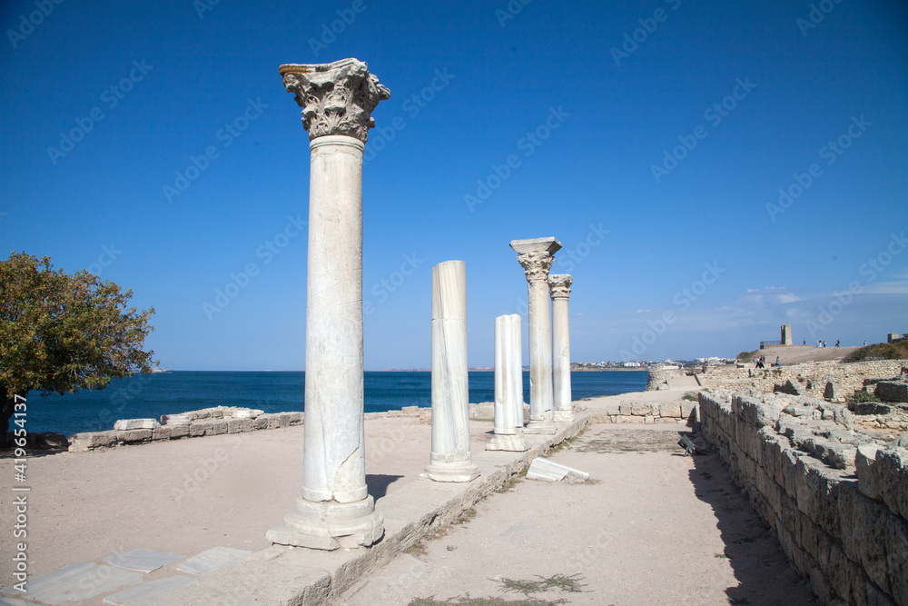 View of the remains of an ancient colonade in the ancient city of Chersonesos against the background of the sky. Crimea. Travel concept.