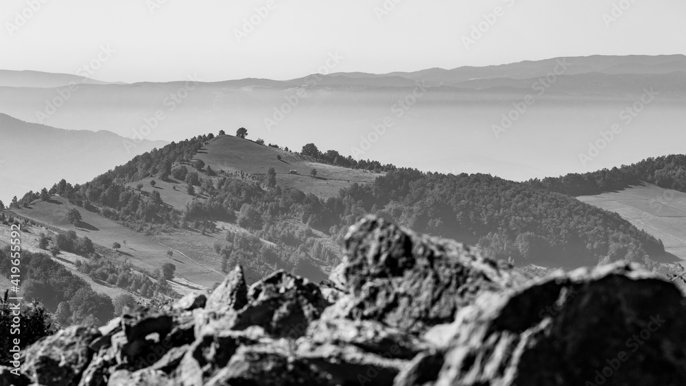Black and white misty mountain landscape, several layers, blurred rocky foreground. The beautiful hills of Western Serbia