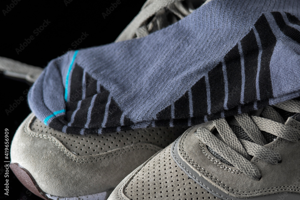 A pair of men's cotton socks lies on a gray leather sneaker, close-up. A pair of men's cotton socks lies on a gray leather sneaker, close-up.