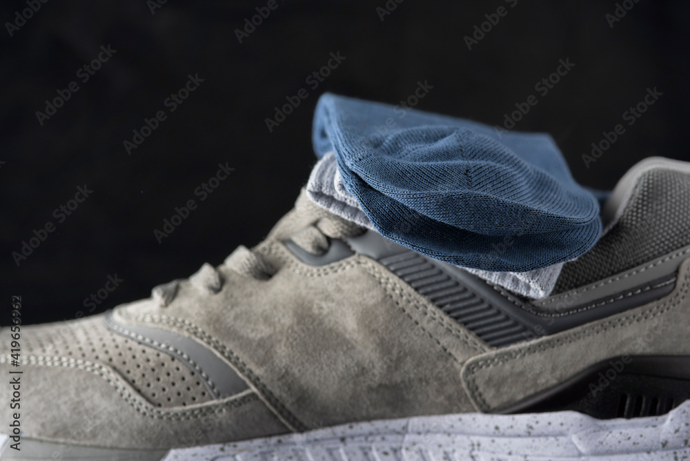 A pair of men's cotton socks lies on a gray leather sneaker, close-up. A pair of men's cotton socks lies on a gray leather sneaker, close-up.