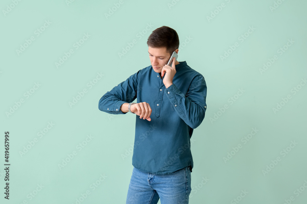 Handsome young man talking by mobile phone on color background Handsome young man talking by mobile phone on color background