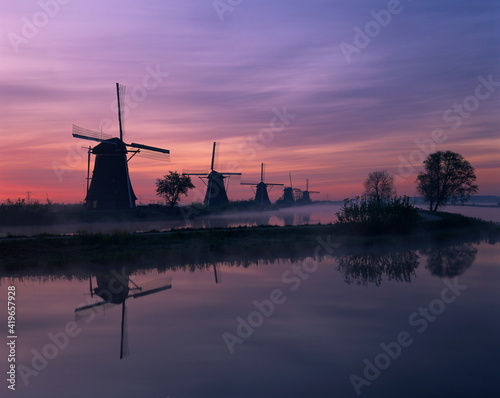 Reflections of a line of windmills in a misty landscape at Kinderdjik, Holland photo