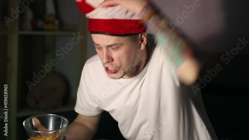 A man with strange hat watching a sport match and get disappointed