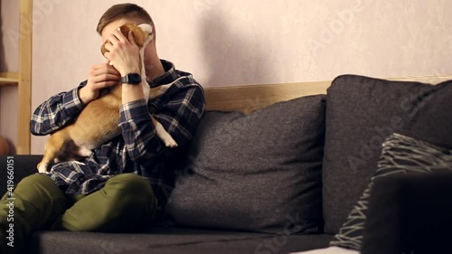Teenager playing with a dog at home.
