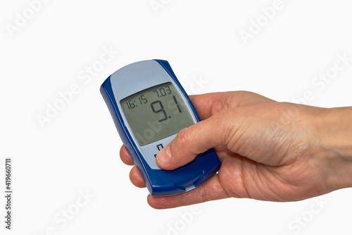 Hand holding glucometer with blood sugar test result.