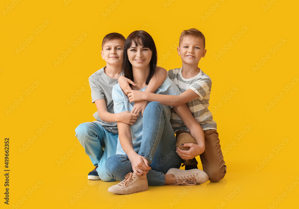 Happy mother and cute children on color background