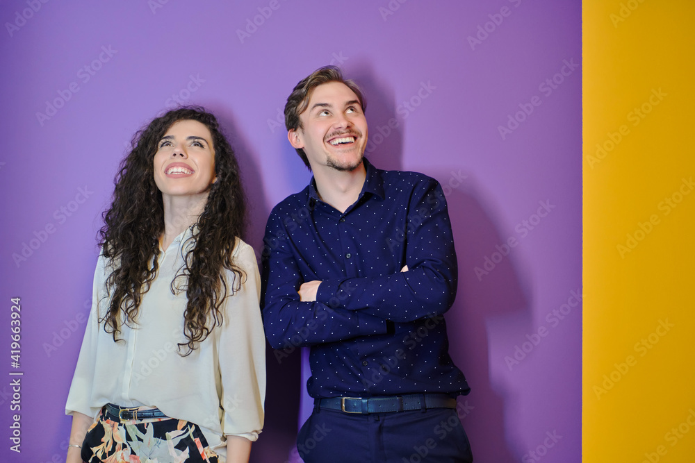 Happy young couple posing on purple background Happy young couple posing on purple background