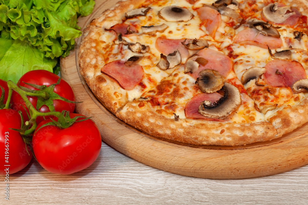Pizza with ham, mushrooms and cheese on a board with tomatoes and green salad Pizza with ham, mushrooms and cheese on a board with tomatoes and green salad