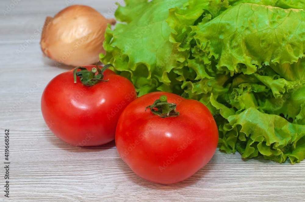 Red tomatoes and lettuce on the table. Vegetarian healthy food Red tomatoes and lettuce on the table. Vegetarian healthy food