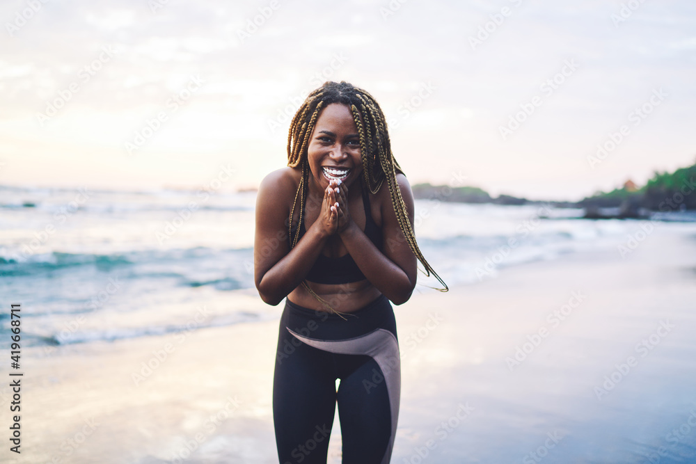 Portrait of cheerful African American woman feeling excited during morning training at coastline smiling at camera, dark skinned jogger dressed in sportive clothes clothes laughing at seashore Portrait of cheerful African American woman feeling excited during morning training at coastline smiling at camera, dark skinned jogger dressed in sportive clothes clothes laughing at seashore
