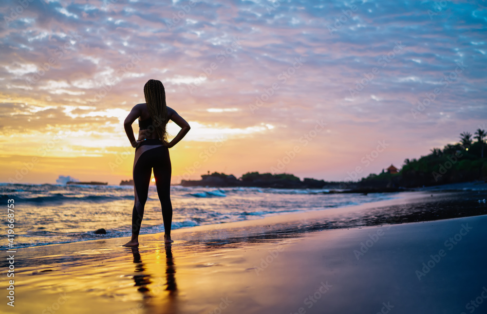 Back view of fit girl in tracksuit looking at scenery landscape spending evening time for enjoying breathtaking sunset and running across seashore coastline, woman with casual figure near ocean Back view of fit girl in tracksuit looking at scenery landscape spending evening time for enjoying breathtaking sunset and running across seashore coastline, woman with casual figure near ocean