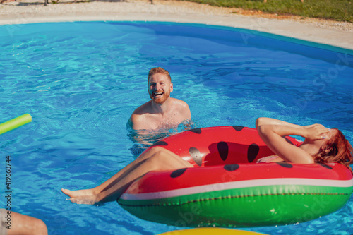 Couple having fun using a swimming float at the pool