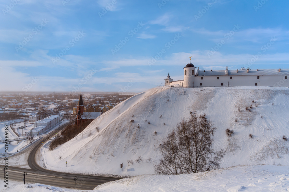 Obraz premium View of Tobolsk (Russia) - an ancient city lying under the mountain and on the mountain in a frosty winter evening. A haze spreads over the city. The houses of the townspeople, churches are visible