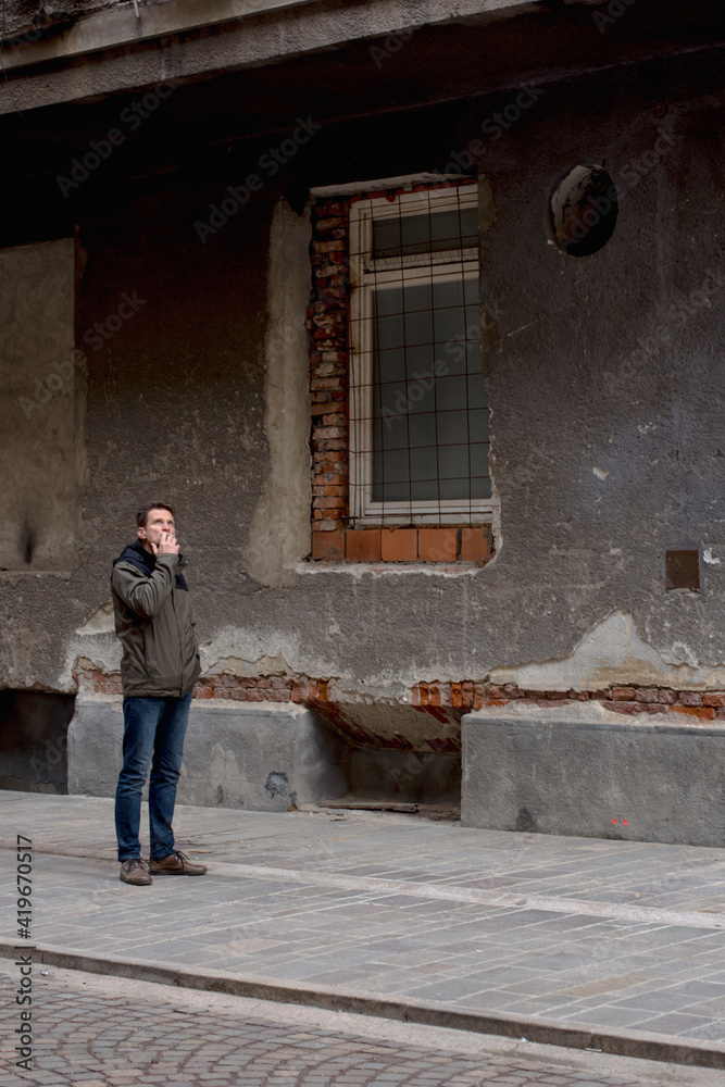 Adult man smoking on the side street near a disused building