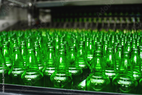 Automated conveyor line in a brewery. Rows of green glass bottles on the conveyor close-up. Industrial brewery