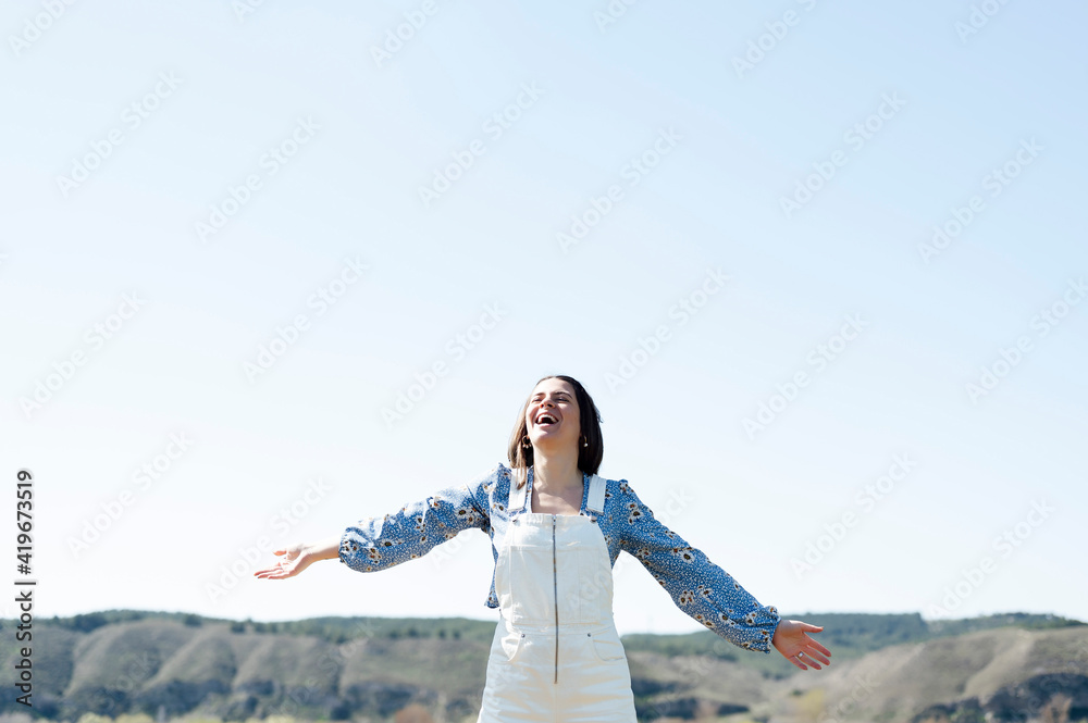 smiling woman with open arms and blue sky in the background smiling woman with open arms and blue sky in the background