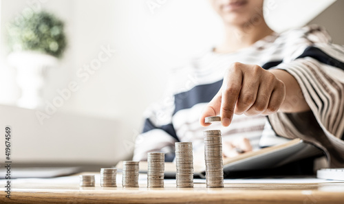 Bilde på lerret Women are stacking coins on top of the coin pile on the highest row