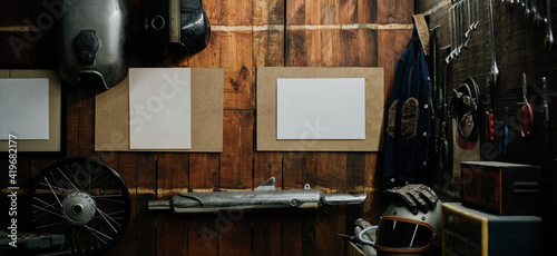 Workshop scene. Old tools hanging on wall in workshop, Tool shelf against a table and wall, vintage garage style, with blank paper