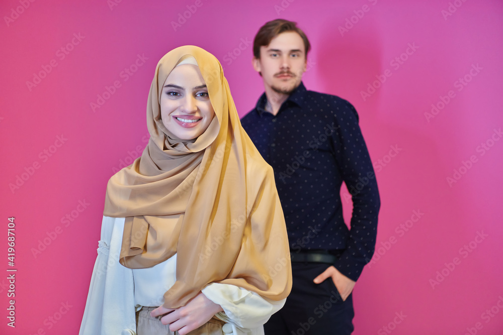 Portrait of happy young muslim couple standing isolated on pink background