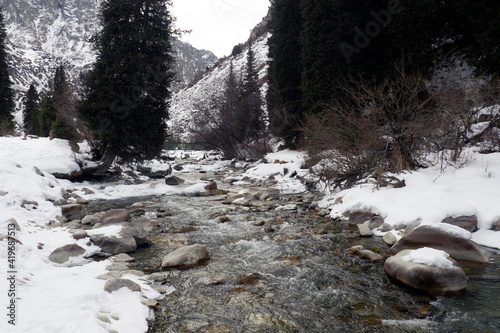 Winter river in a snow-capped mountain gorge. Kyrgyzstan. Ala-Archa.