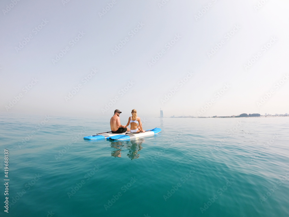 Active Couple on the paddle boards with a view on Burj Al Arab Active Couple on the paddle boards with a view on Burj Al Arab