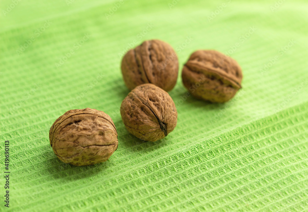 Four whole walnuts lie on a green kitchen towel Four whole walnuts lie on a green kitchen towel