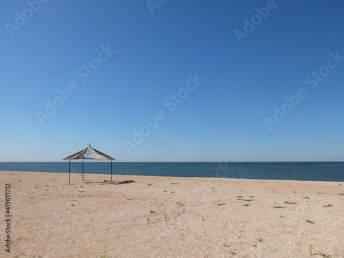 Minimalistic landscape of sandy coastline with old gazebo or pavilion