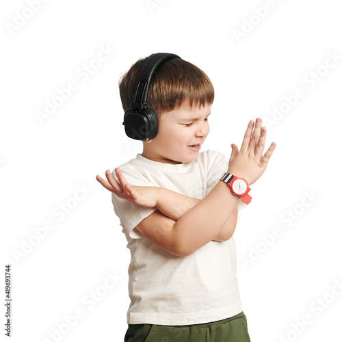 isolated child in headphones listens to music and sings on white background. happy little boy. cross arms.