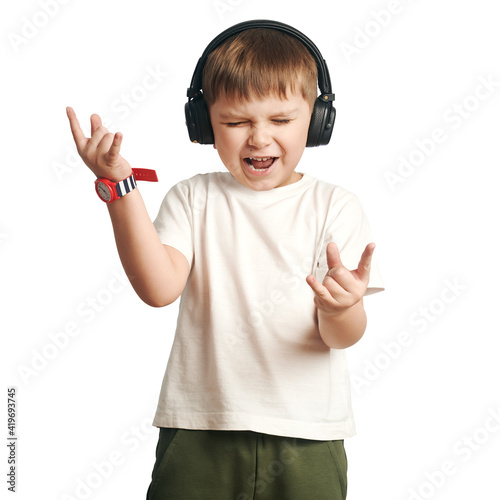 
isolated boy listens to music on headphones and shows on fingers the sign rock on white background. 