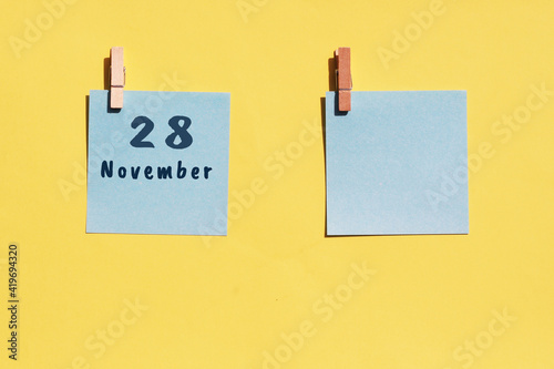 28 november. 28th day of the month, calendar date. Two blue sheets for writing on a yellow background. Top view, copy space. Autumn month, day of the year concept