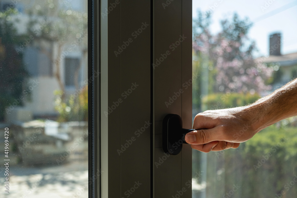 Aluminum window frame detail. Male hand opens the metal door closeup view. Aluminum window frame detail. Male hand opens the metal door closeup view.