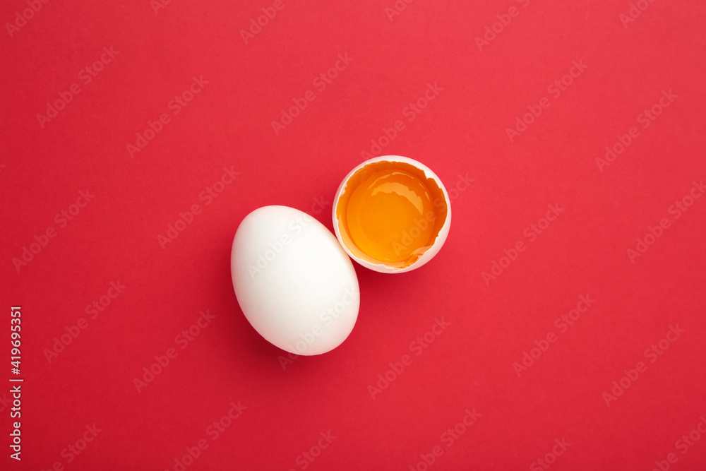 White eggs and egg yolk on the red background. Easter concept