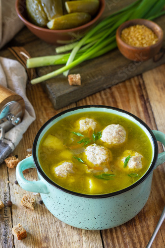 Healthy and diet food. Soup with meatballs and bulgur on a wooden table.