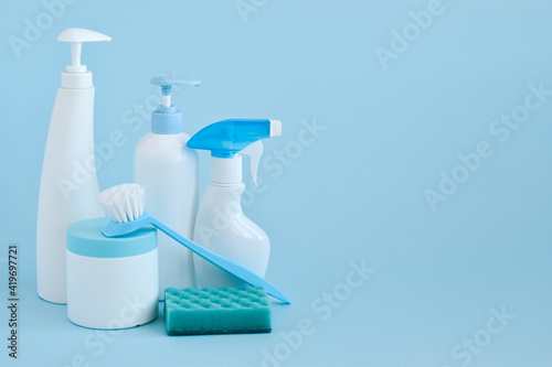 Cleaning products and sponges on light blue. Bottles of detergent and water. The concept of cleaning in the house, apartment, office. Household chemicals. Spring.
