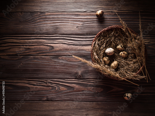 Quail eggs in a basket. Dark wooden background. View from above