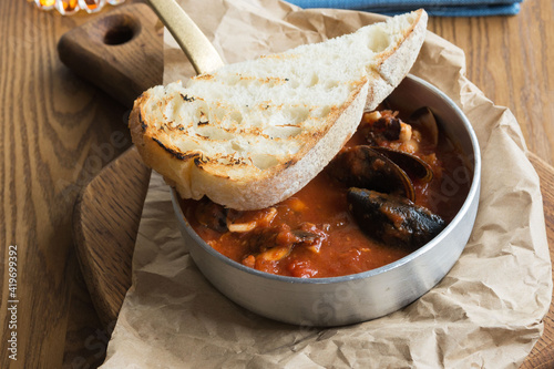 Delicious hearty lunch at a fish restaurant. Tuscan tomato soup with seafood Cacciucca. Cacciucco is a mixture of fish broth, red wine and tomato sauce. photo