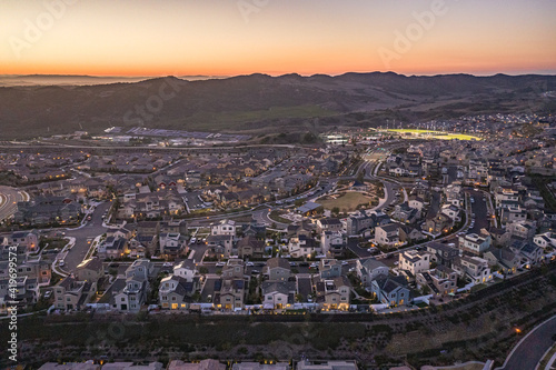 Aerial Summertime Sunset View Of Suburban Upscale California Neighborhood Community With Lit Baseball Field And Track Homes photo