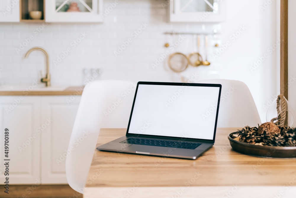 Laptop computer with white blank screen mock up, on the bright modern kitchen table. Laptop computer with white blank screen mock up, on the bright modern kitchen table.