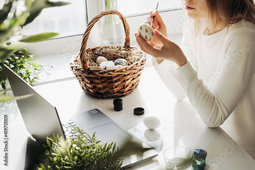 Obraz na plátně Young woman studying at home and decorating Easter eggs with natural pattern