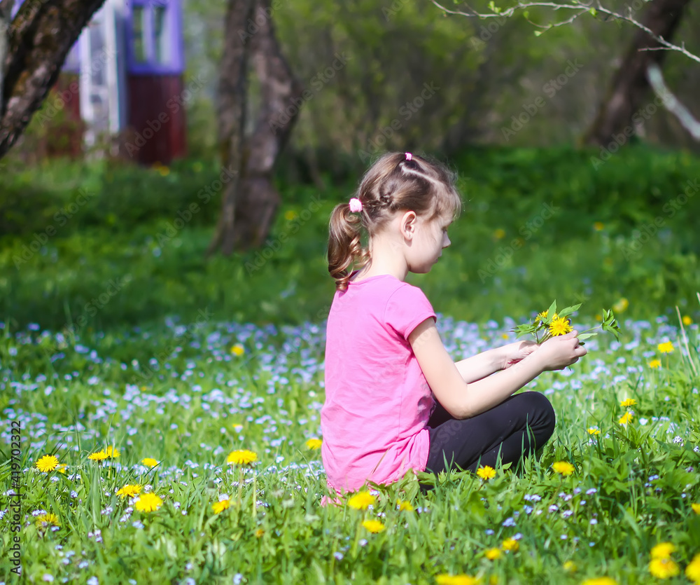 A girl on the green spring meadow with a lot of wildflowers in sunlight. Child exploring nature. A girl on the green spring meadow with a lot of wildflowers in sunlight. Child exploring nature.