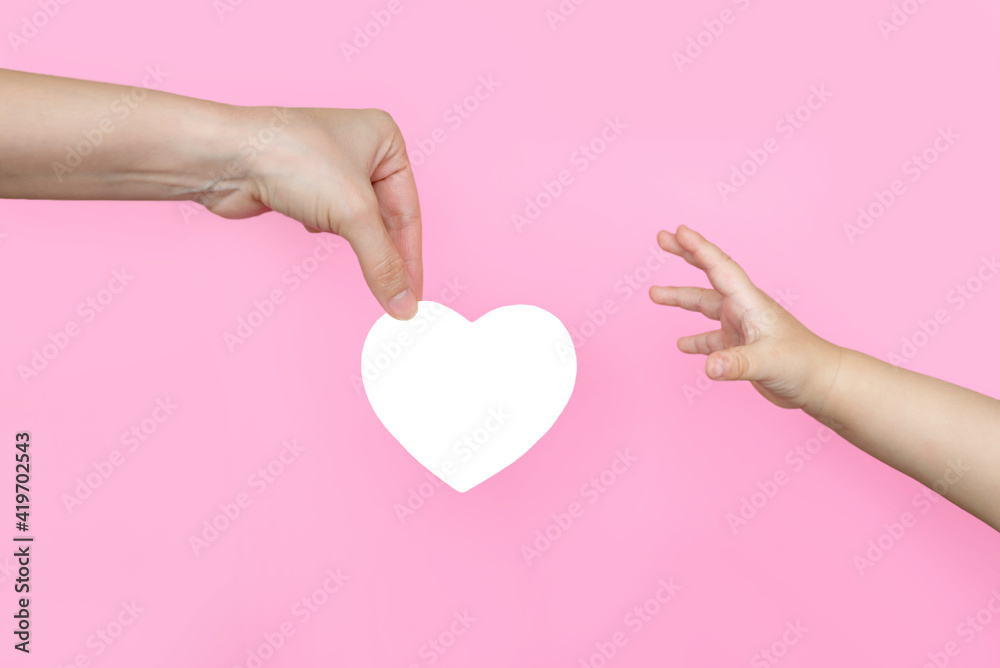 an adult gives a heart to a small child. the concept of child support, charity and social assistance