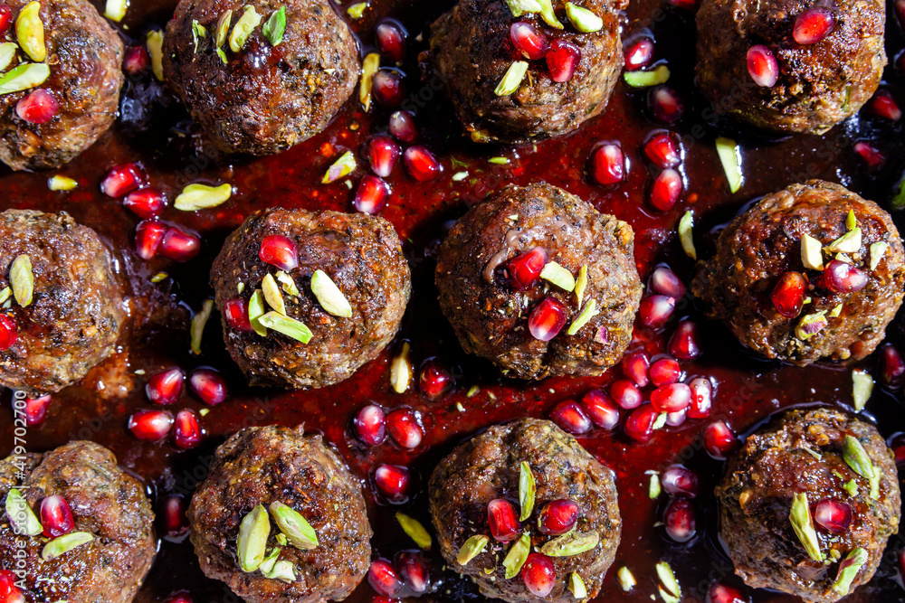 Baked meatballs with pomegranate (seeds, juice and molasses) and pistachio nuts. Cooked at home.