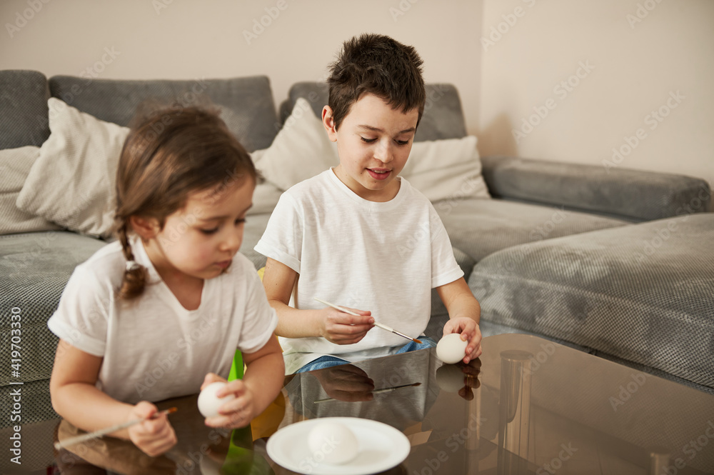 Two adorable children holding eggs and paintbrushes ready for coloring Easter eggs. Two adorable children holding eggs and paintbrushes ready for coloring Easter eggs.