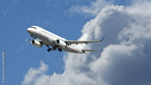 Zoom photo of passenger airplane flying above clouds in deep blue sky